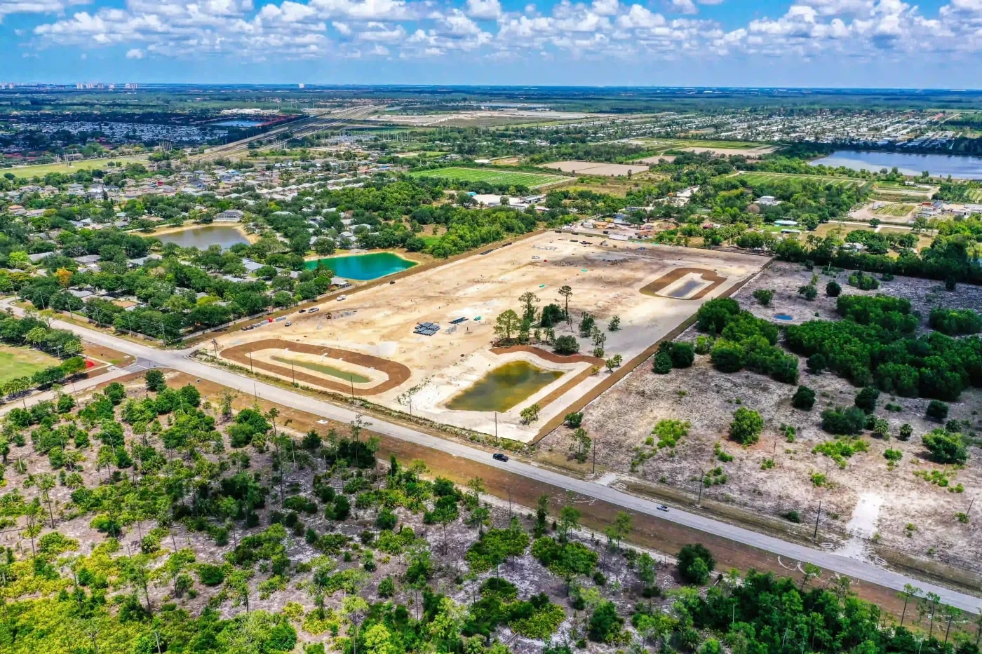 Drone capture of land grading in early development phase with retention ponds and surrounding suburban density