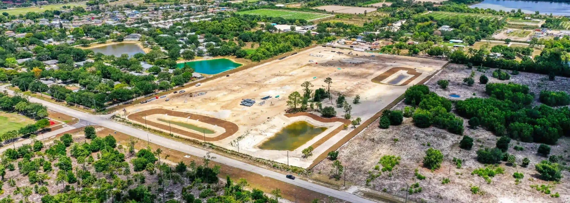 Drone capture of land grading in early development phase with retention ponds and surrounding suburban density
