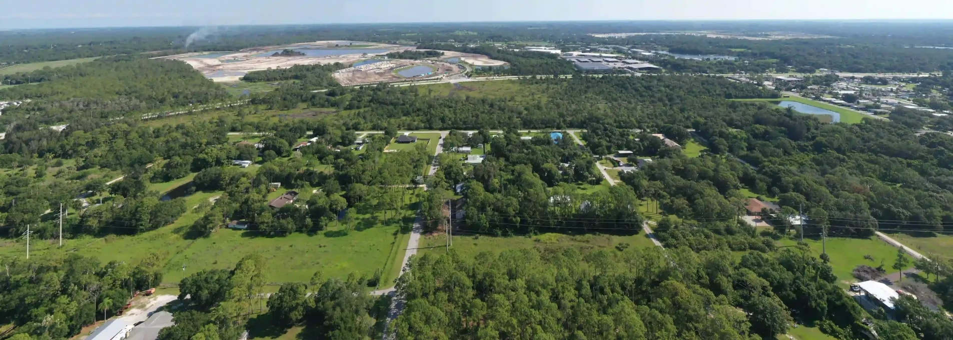 Drone photo of a semi-rural area with scattered homes, open land, and industrial development visible on the horizon