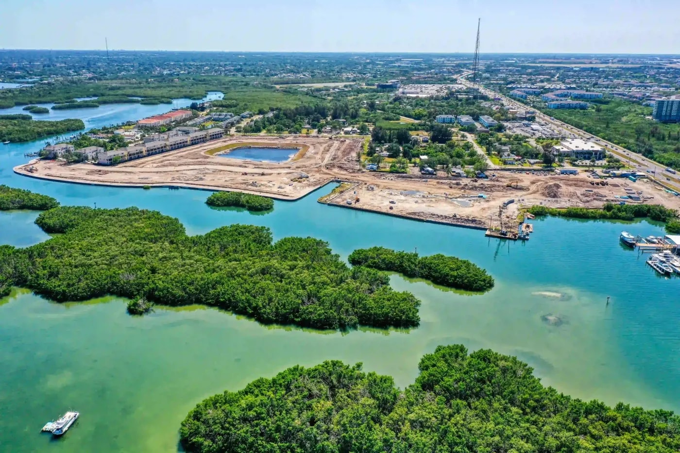 Active construction site along coastal wetlands with nearby residential infrastructure and marine access channels